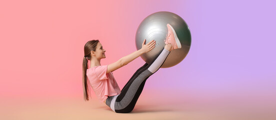 Sporty young woman training with fitball against color background