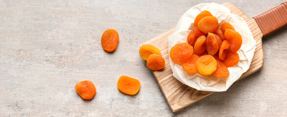 Board with tasty dried apricots on grunge background with space for text