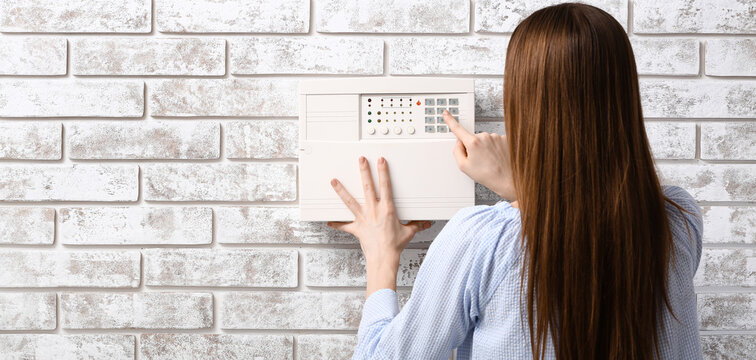 Young woman using smart home security system in room