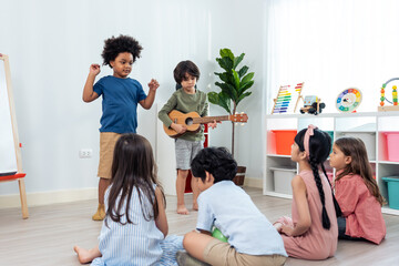 Group of Mixed race young little kid play guitar music in schoolroom.