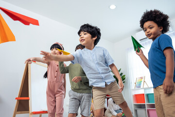 Group of Mixed race young little kid playing airplane in schoolroom.