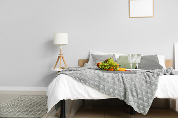 Interior of modern bedroom with fruit basket and empty glasses on bed
