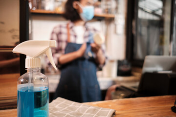 Alcohol sanitizer for healthy protection in a cafe, Asian male barista in face mask use laptop, waiting for coffee order in COVID19 pandemic quarantine, the economic impact for small business startup.