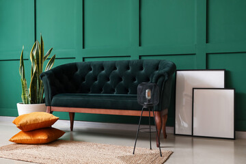 Stylish sofa and houseplant near green wall