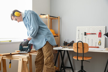 Male carpenter sawing wood in workshop