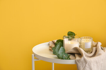 Holders with burning candles and eucalyptus branch on table