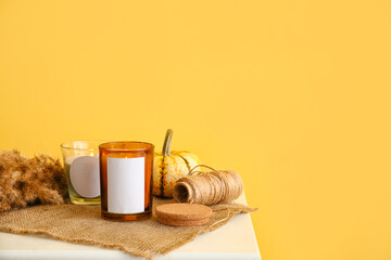 Holders with burning candles and reed branch on table