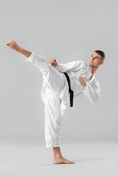 Man practicing karate on light background