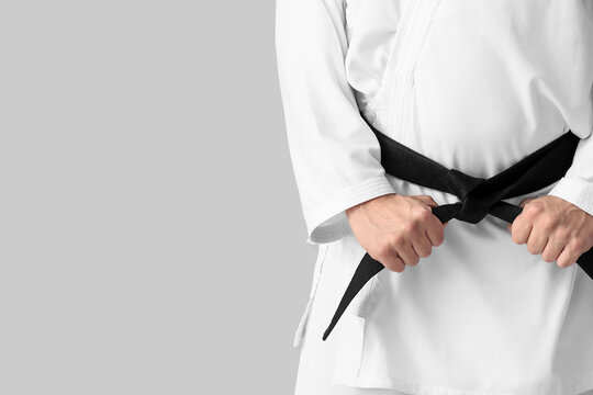 Man In Karategi And With Black Belt On Light Background, Closeup