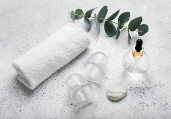 Composition with bottle of essential oil, clean towel and vacuum jars for anti-cellulite massage on...