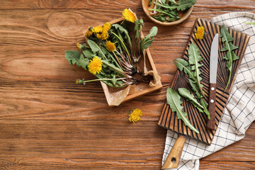 Board, box and bowl with dandelions, napkin and knife on wooden background