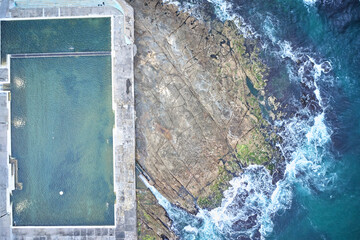 Newcastle Ocean Baths aerial photo with swimmer in ocean bath at sunrise