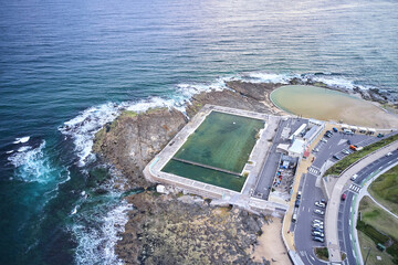 Newcastle Ocean Baths aerial photo with swimmer in ocean bath at sunrise