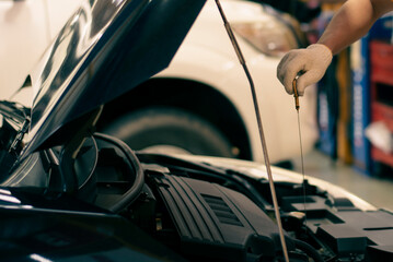 Close up image hand of young man mechanic in car service center is checking the engine. For...