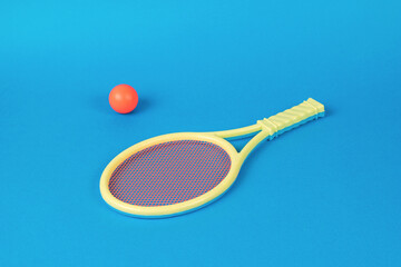 A yellow racket with an orange net and an orange ball on a blue background.