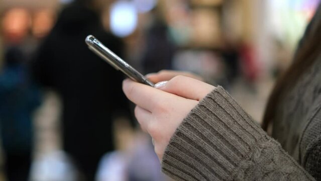 Shopping center. Moll. Finger of woman touching scroll page app on mobile phone. Browsing movie video in the internet library to watch film online.