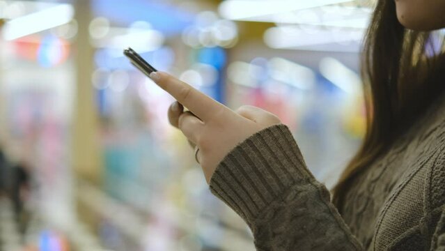 Shopping center. Moll. Finger of woman touching scroll page app on mobile phone. Browsing movie video in the internet library to watch film online.