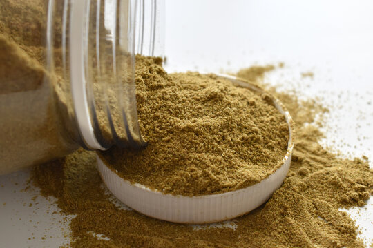 Cumin powder spilling out of a plastic jar. 