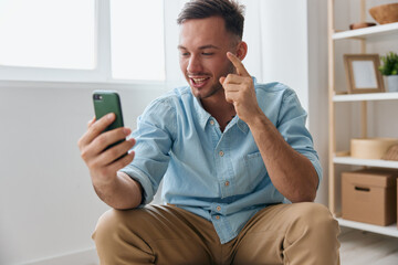 Cheerful smiling communicative guy talk with family using phone video call discusses the latest pleasant news raise finger up looks at screen. Distance communication Video conference Gadget concept