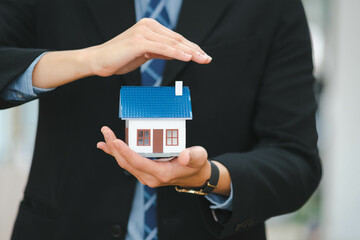 Businessman holding a house model.