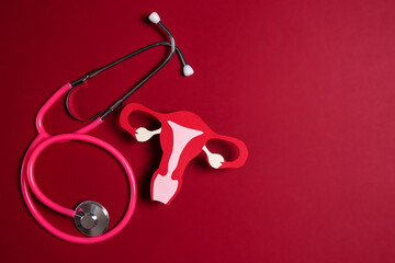 Women's health awareness concept. Uterus symbol with stethoscope on red background. Diagnostic and research women's reproductive system. - obrazy, fototapety, plakaty