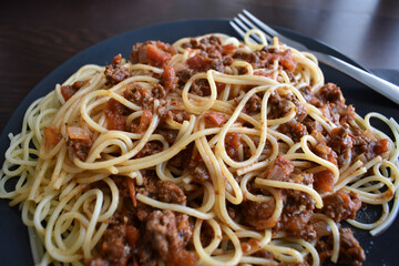 Spaghetti Bolognese with minced beef, onion, chopped tomato, garlic, olive oil, stock cube, tomato puree and Italian herb. Traditional Italian food on a plate.	
