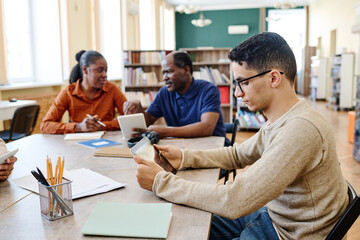 Young Middle Eastern student and his Black classmates attending lesson for immigrants in library...