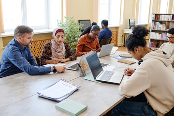 Group of multi-ethnic people having integration and language classes using laptops to do writing task