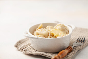 Appetizing homemade Russian dumplings pelmeni stuffed with meat mince with butter in a bowl on the table.