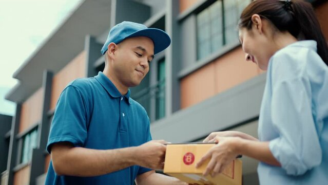 Young woman signing electronic Signature on tablet for agreement of contract digital receiving parcel from blue delivery man from shopping online. Courier man delivering package to destination.