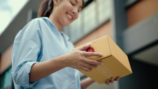 Close up parcel in hand of blue uniform delivery man to customer front of the house with good service from shopping online. Courier man delivering a cardboard box postal package to destination.