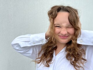 a girl on a white background a teenager covers her ears with both hands She does not want to hear...