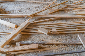 Carpentry waste is covered with sawdust on the floor. Wooden planks and beams for recycling