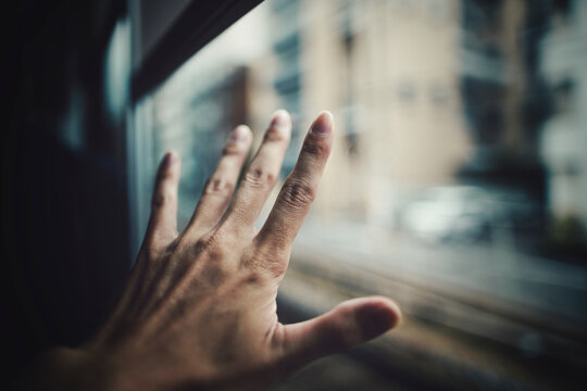 窓ガラスに触れる男性の手