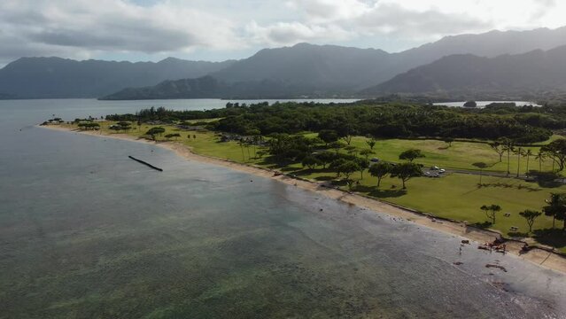 4K cinematic clockwise drone shot of waves quietly crashing at Kualoa Beach Park in Oahu. This calm, picturesque Hawaiian scene was filmed using a DJI Mini 2 drone.