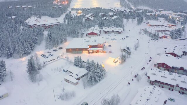 Drone aerial tilt down, Levi, Finland with bus and pedestrians on road ski village