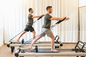 Fototapeta na wymiar Fit men exercising on pilates machines in gym