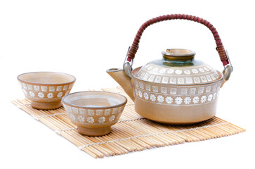 Closeup of teapot and teacup set Japanese style put on bamboo mat isolated on white background. - obrazy, fototapety, plakaty
