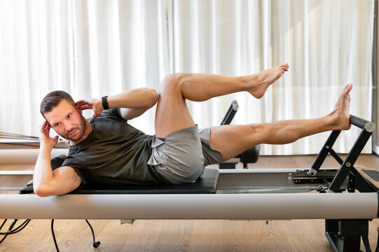 Fit man doing crisscross crunches during training on pilates machine