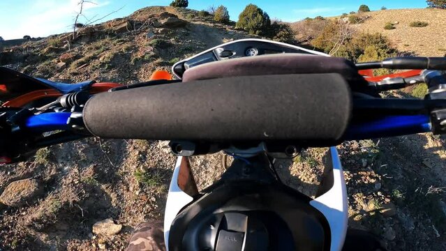 Steering wheel Handlebars view motorcyclist climbing dangerous off-road mountain range on enduro motorbike