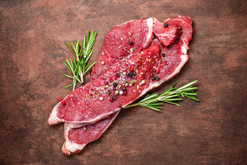 Fresh beef steak meat on old wooden table. Raw meat with spices, salt and rosemary herb. Copyspace. Top view.