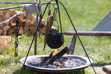 Food is cooked in a cauldron on a fire near the tents