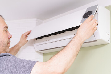 Fototapeta premium a man removes the cover of the air conditioner for the cleaning indoors