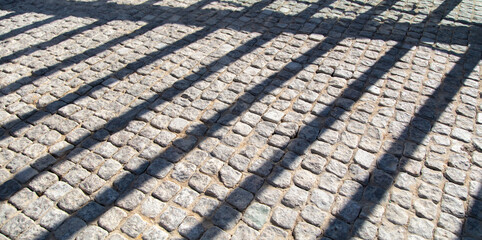 The shadow from the fence on the stone paving stones as an abstract background.