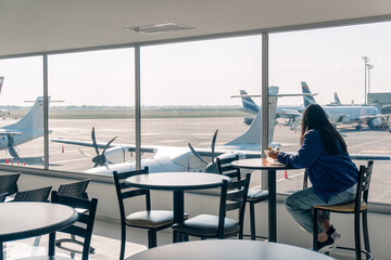 Airport: Traveler woman at the airport taking a break as she prepares for the flight. woman in the departure lounge waiting for her flight. operations corresponding to the performance of a flight 