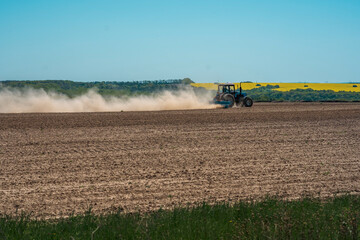 Obraz premium spring sowing agricultural crops, tractor works on the field ukraine agrarian sunny day