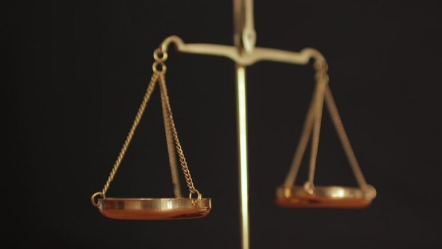 Golden justice scales close up on black background