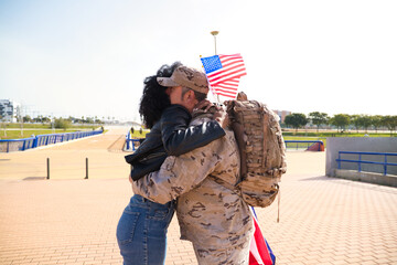 Afro-American woman and soldier who has just returned from war on a mission embrace each other...