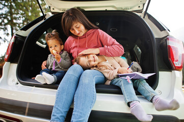 Family at vehicle interior. Mother with her daughters. Children in trunk. Traveling by car in the mountains, atmosphere concept.