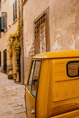 A typical Italian three-wheeler in the narrow medieval lanes of Castiglione della Pescaia, an old...